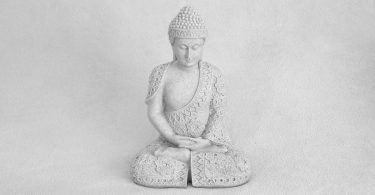 A person meditating outdoors with calm, slow breathing in a peaceful natural setting.